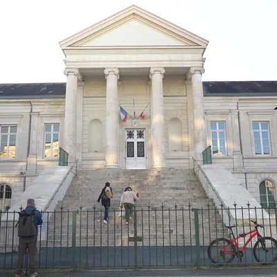 Le palais de justice de Châteauroux, un bâtiment néoclassique avec des colonnes et des drapeaux.