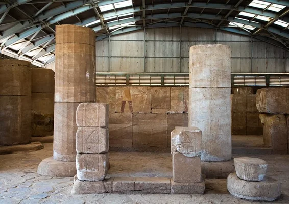 Colonnes de pierre anciennes exposées dans une structure couverte du Musée national du Soudan, avec un mur de fond orné de hiéroglyphes.