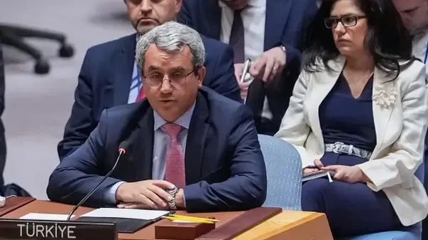 Un représentant turc s'exprime à un micro devant un panneau indiquant TÜRKİYE.