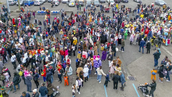 Foule nombreuse en costumes colorés participant à un événement festif dans un parking à Lyon.
