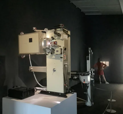 Un projecteur de film IMAX 15/70 mm vintage exposé sur un piédestal.