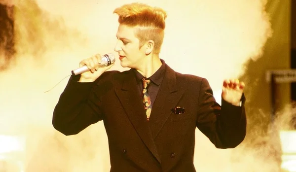 Desireless chantant Voyage Voyage sur scène avec un micro.