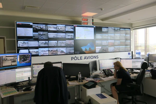 La salle de contrôle 'Pôle Avions' d'un aéroport avec ses nombreux écrans de surveillance et son personnel au travail.
