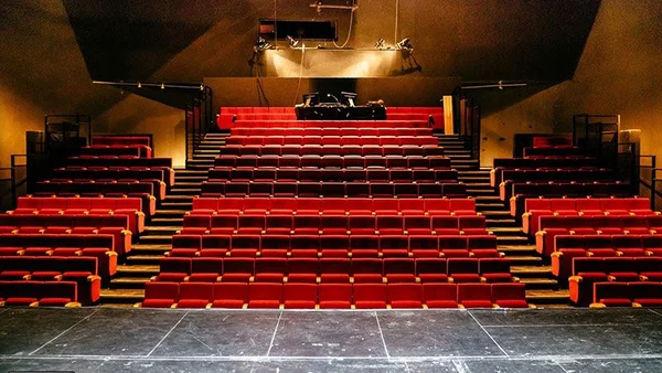 Vue de la salle des Plateaux Sauvages avec ses sièges rouges en amphithéâtre face à la scène.