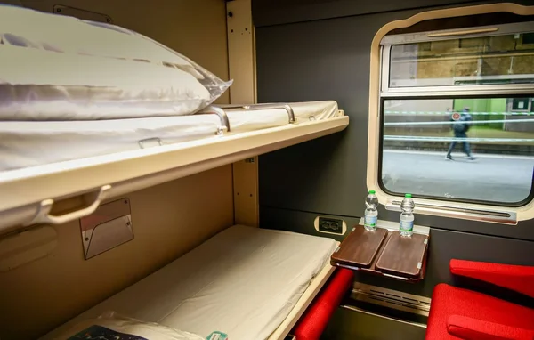 L'intérieur d'une couchette du train avec des lits superposés et une table.