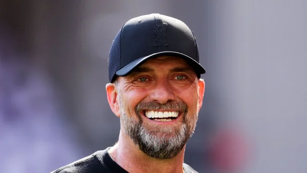 Jürgen Klopp souriant en casquette et t-shirt noirs du Liverpool FC.