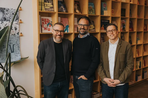 Les responsables des éditions La Pastèque et Bayard Canada réunis devant une bibliothèque.