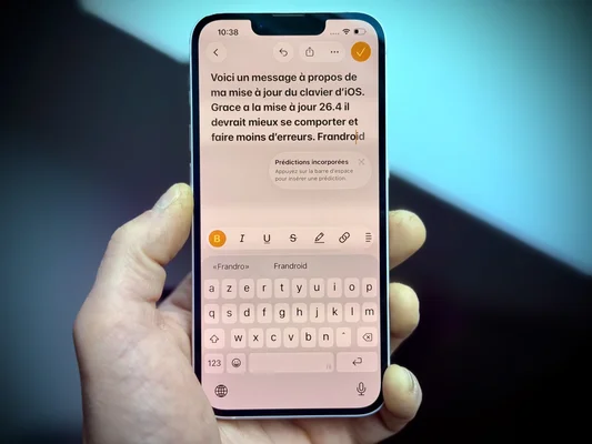 Une main tient un iPhone montrant un message et le clavier de saisie.