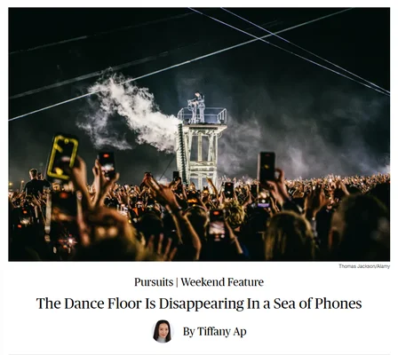 Un artiste sur scène entouré d'une foule levant une mer de téléphones pour enregistrer.