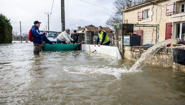 Des sinistrés pompent l'eau dans la rue pour tenter de déblayer les zones inondées.