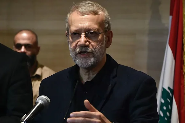 Ali Larijani s'exprimant au micro, avec le drapeau libanais en arrière-plan.