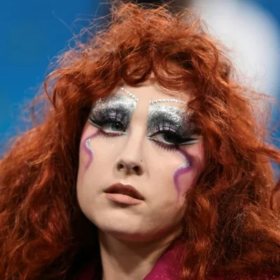 Gros plan de Chappell Roan avec un maquillage yeux élaboré aux paillettes argentées.