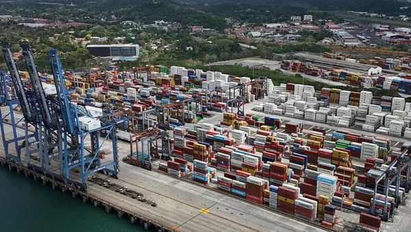 Vue aérienne d'un port à conteneurs animé avec de grandes grues bleues.