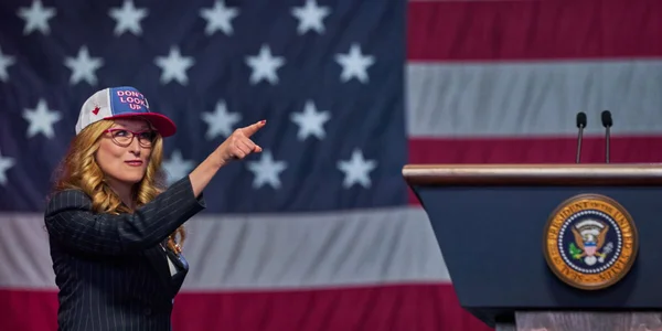 Meryl Streep en costume rayé et casquette Don't Look Up devant un drapeau américain et un pupitre présidentiel.