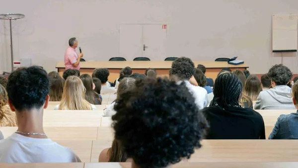 Intervenant prenant la parole devant un public étudiant assis dans une salle de cours.