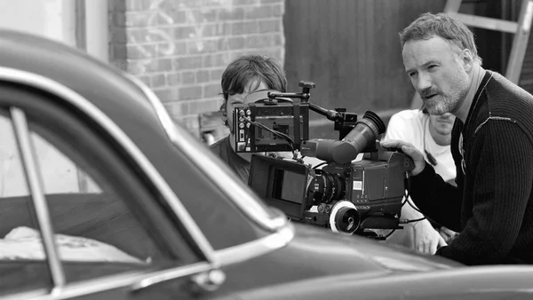 David Fincher et son équipe au travail sur un plateau près d'une voiture ancienne.
