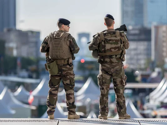 Soldats français surveillant un campement militaire en zone urbaine.