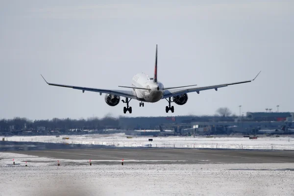 Un avion de ligne en approche finale sur une piste enneigée.