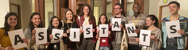 Un groupe de participants formant le mot ASSISTANTS lors d'un événement France Éducation International.