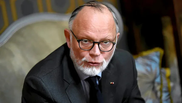 Édouard Philippe assis dans un salon orné, portant un costume sombre