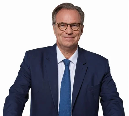 Renaud Muselier, assis en costume bleu, s'exprimant dans un bureau aux murs rouges.