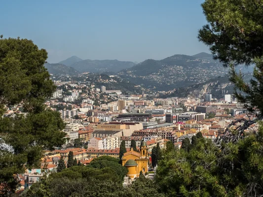 Vue panoramique de la ville de Nice, lieu des obsèques de Loana, avec son architecture caractéristique et les collines en arrière-plan.
