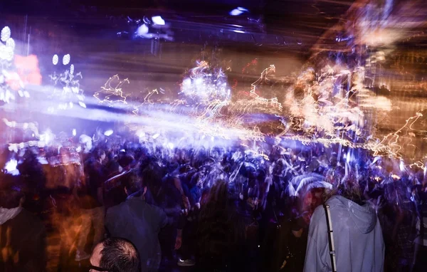 Foule dense à l'intérieur lors d'un événement festif aux lumières vives.