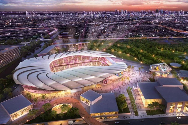 Le stade illuminé se détachant sur la skyline urbaine au crépuscule.
