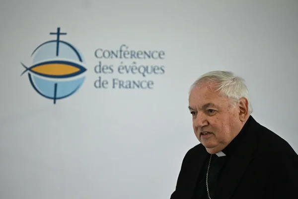Un représentant de l'Église devant le logo de la Conférence des évêques de France.