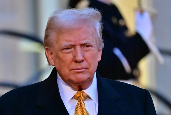 Donald Trump portant une cravate jaune motifée devant un fond flou.