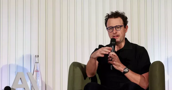 Un homme en costume et lunettes bleues lors d'un événement officiel.