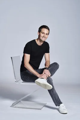 Evan Spiegel, PDG de Snap, assis sur une chaise en acrylique transparent et souriant à la caméra.
