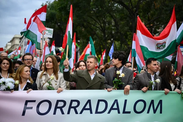 Manifestants avec des drapeaux et une bannière "FORRADALOM" dans la rue.