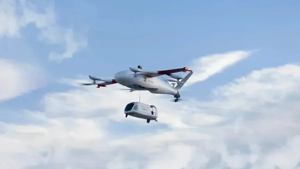 Un drone Zipline en vol avec sa nacelle de livraison suspendue sous le fuselage.
