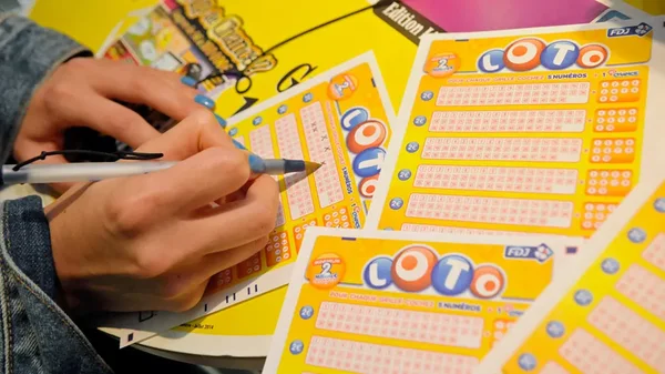 Un joueur remplissant des grilles LOTO jaunes avec un stylo, préparant sa validation.