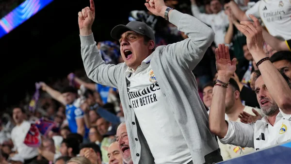 Un supporter en maillot du Real Madrid célébrant parmi la foule dans les tribunes.