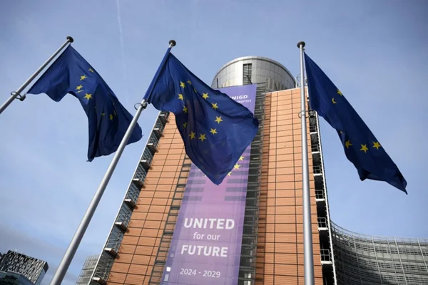 Drapeaux européens devant un bâtiment institutionnel, illustrant la volonté de l'UE de clarifier les modalités d'assistance mutuelle.