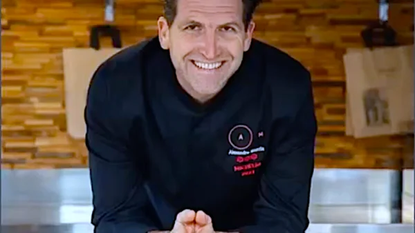 Le chef Alexandre Mazzia posant devant un mur en bois.