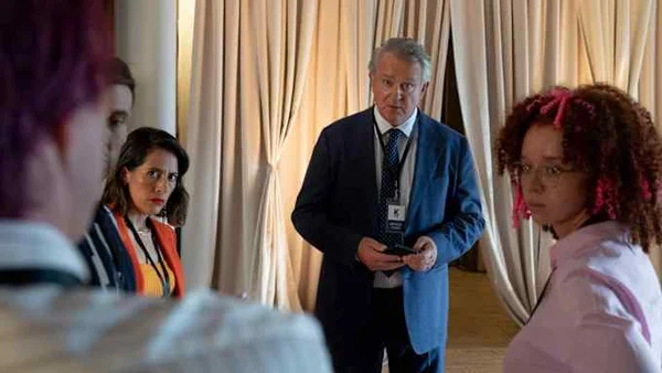 Katya Adler avec un homme en costume bleu tenant un appareil et une femme en veste rayée