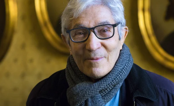 Boualem Sansal debout devant un décor orné de cercles dorés.