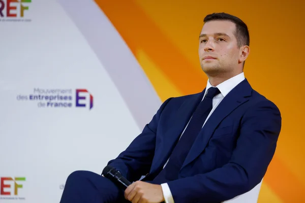 François Durvye en chemise blanche, barbu et portant des lunettes, dans un intérieur lumineux.