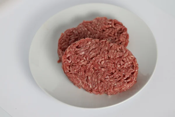 Viande hachée servie sur assiette blanche sur fond clair.