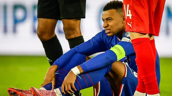 Kylian Mbappé au sol, souffrant d'une blessure à la jambe.