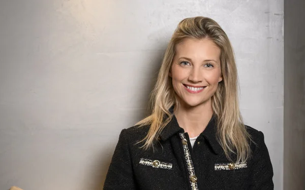 Audrey Lefèvre en veste noire ornée de dorures, souriant devant un fond gris.