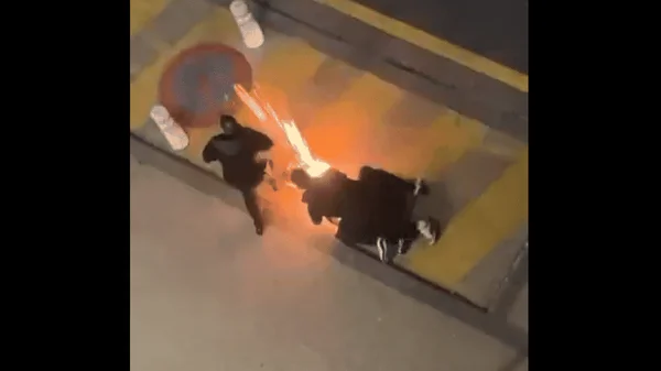 Une scène à Noisiel où une flamme orange apparaît entre deux personnes sur le sol pavé, lors de l'interpellation de Flavel.