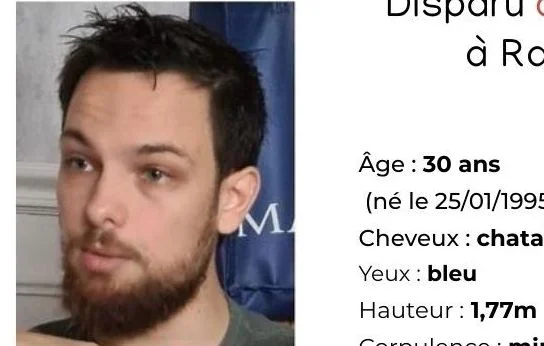 Clément Besneville assis, barbu et luné, portant une chemise à carreaux.