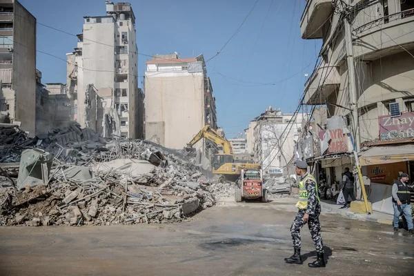 Opérations de déblaiement dans une rue de Beyrouth avec des engins de chantier et un soldat au premier plan.