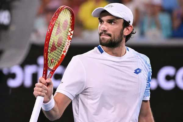 Valentin Vacherot sur un court de tennis, raquette à la main, prêt à servir.