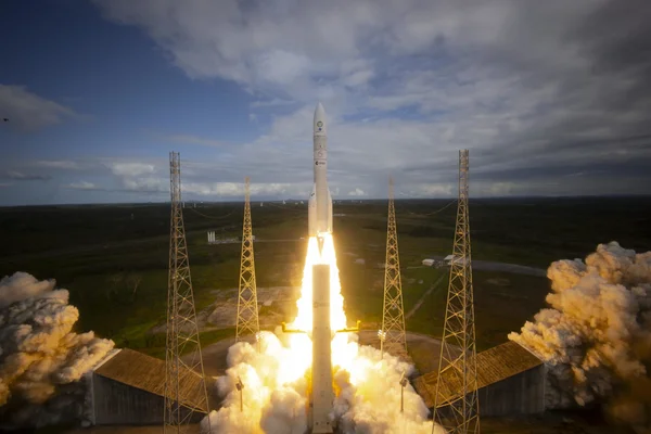Décollage d'Ariane 6 entouré de flammes et de fumée.