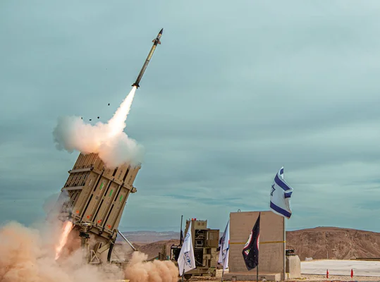 Lancement d'un missile dans un désert avec un drapeau israélien à proximité.